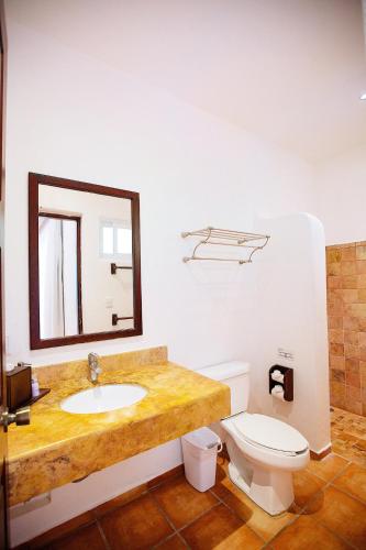 a bathroom with a sink and a toilet and a mirror at Hotel Rancho Encantado in Bacalar
