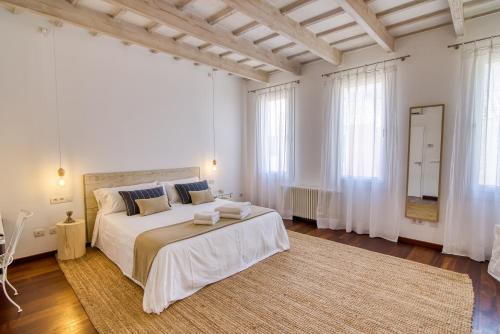a white bedroom with a large bed and a large window at Hotel Ca S'Arader Turismo de Interior in Ciutadella