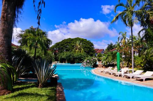 a pool at a resort with lounge chairs and palm trees at Woburn Residence Club in Malindi