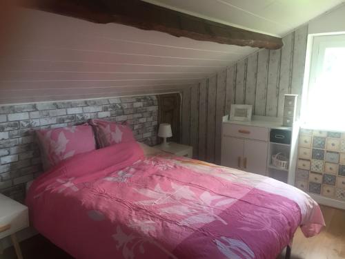 Saint-DiéryにあるUn bol d’air à la campagneのピンクベッド1台付きのベッドルーム1室、レンガの壁