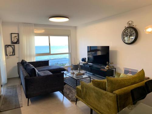 a living room with two couches and a television at sea view in ‘Akko