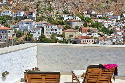 a view of a city from a balcony with two chairs at Onar Hydra in Hydra