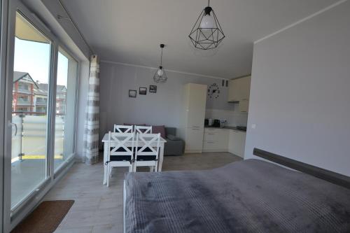 ein Schlafzimmer mit einem Bett und einem Tisch sowie eine Küche in der Unterkunft Darłówko Apartament Morski V in Darłówko