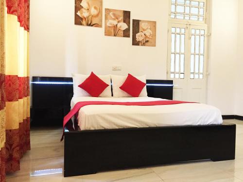 a bedroom with a bed with red pillows at Grand Villa Negombo in Negombo