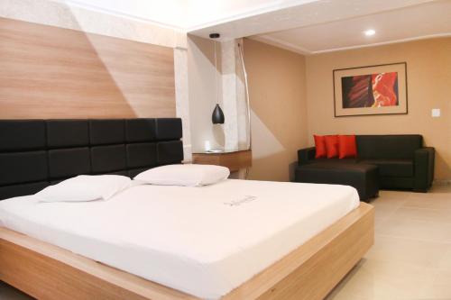 a bedroom with a large bed and a couch at Motel Hollywood in Salvador
