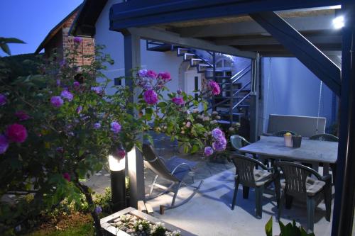 a patio with a table and chairs and purple flowers at House Burić in Otočac