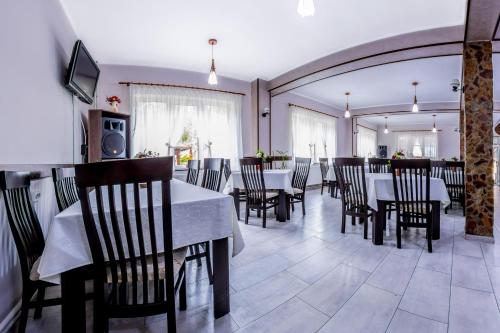 a dining room with tables and chairs and a television at Vila Nico in Baia de Fier