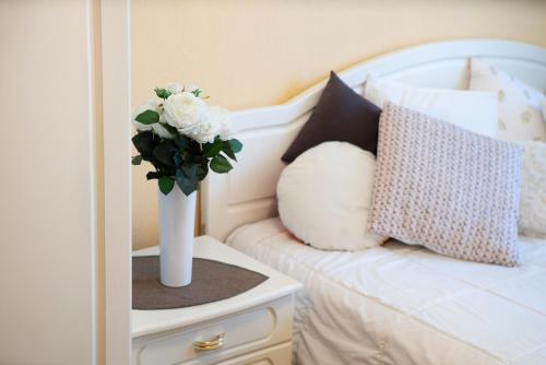 a vase of flowers sitting on a table next to a bed at Comfort 3-Room Apartment with Forest View & 2 Bedrooms in Jūrmala