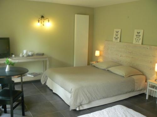 a bedroom with a large bed with a desk and a table at Au Cèdre d'Or B&B in Lambersart