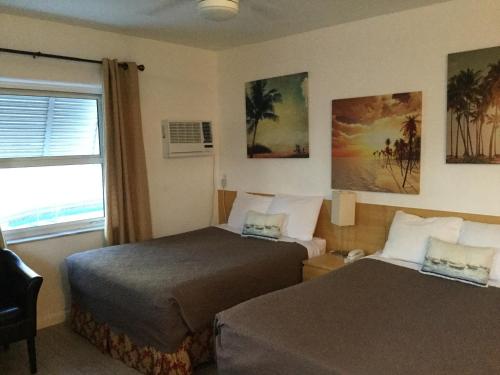 a hotel room with two beds and a window at Breakaway Inn Guest House in Fort Lauderdale