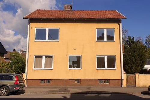 a yellow house with white windows on a street at Lilla Kari in Varberg