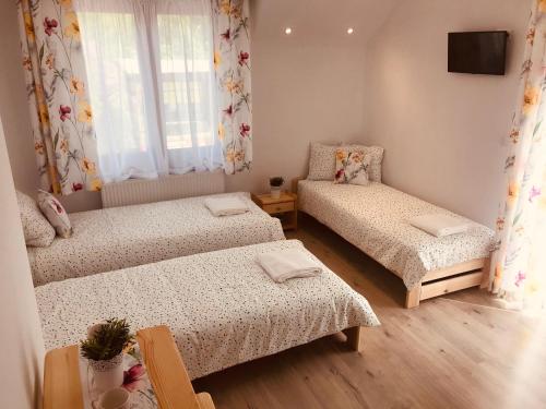 niewielka sypialnia z 2 łóżkami i telewizorem w obiekcie Pokoje Gościnne Lena w miejscowości Święta Katarzyna