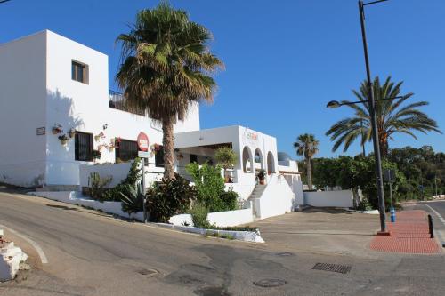 a white building with palm trees in front of a street at Casaflor in Mojácar