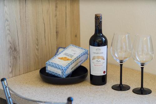 a bottle of wine and two wine glasses on a counter at Comfort 3-Room Apartment with Forest View & 2 Bedrooms in Jūrmala