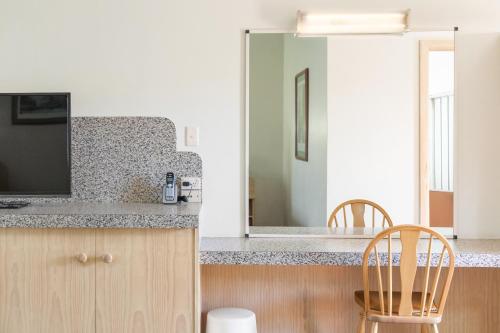 a kitchen with a counter with a television and two chairs at Presidential Motel in Mount Gambier