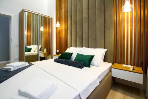 een slaapkamer met een groot wit bed met groene kussens bij MIANELLY CENTER 1 in Constanţa