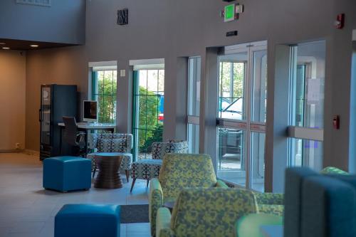a waiting room with chairs and a table and windows at Clarion Pointe Indianapolis Airport in Plainfield