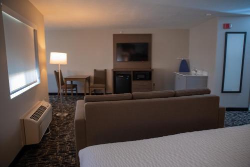 a hotel room with a couch and a tv at Clarion Pointe Indianapolis Airport in Plainfield