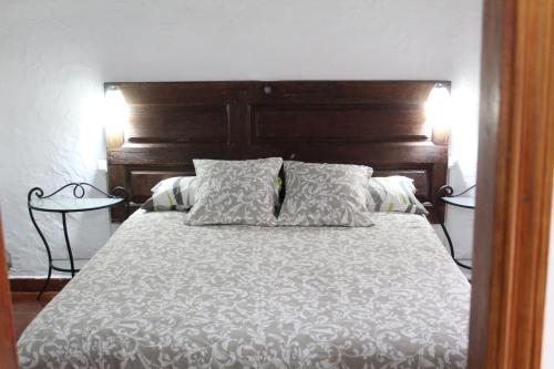 a bedroom with a bed with a wooden headboard and pillows at Capellania in Tijarafe