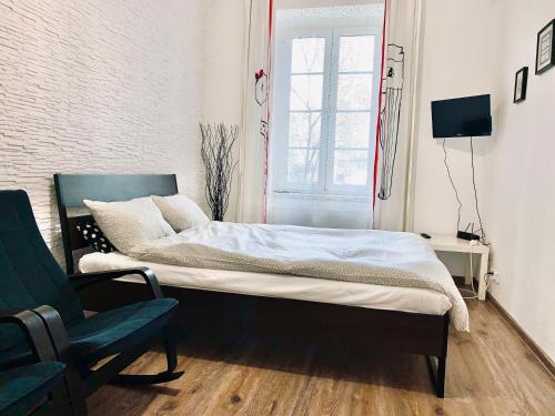 a bed in a room with a chair and a window at Apartament w centrum :) in Krakow
