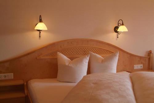 a bedroom with a bed with white pillows and two lights at Hotel-Garni Weidacherhof in Leutasch