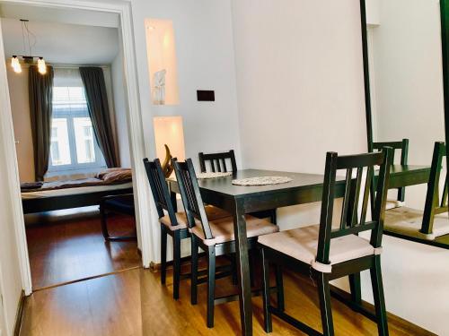 uma sala de jantar com uma mesa preta e cadeiras em Main Square Apartment em Cracóvia