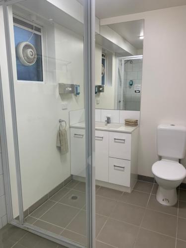 a bathroom with a toilet and a glass shower at Adina Place Motel Apartments in Launceston