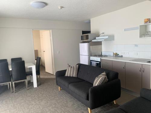 a living room with a couch and a kitchen at Adina Place Motel Apartments in Launceston