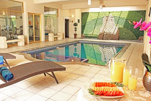 a pool with a table with a plate of fruit and juice at Plaza de Oro in Monterrey