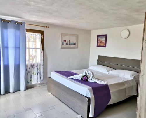 サン・ヴィート・ロ・カーポにあるCasa Vacanze Lillaのベッドルーム(紫の毛布を使用した大型ベッド1台付)