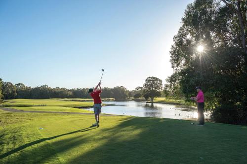 un hombre balanceando un club de golf en un campo de golf en Noosa Springs Golf & Spa Resort, en Noosa Heads