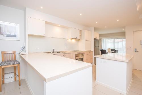 a kitchen with white cabinets and a counter top at Noosa Springs Golf & Spa Resort in Noosa Heads