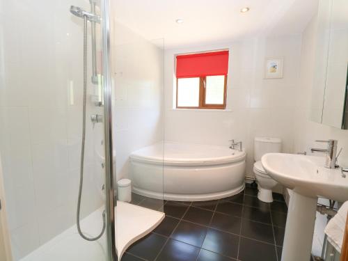 a bathroom with a tub and a toilet and a sink at Meadow View in East Harling