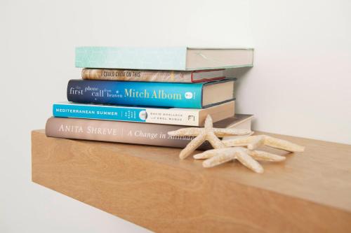 a stack of books sitting on a shelf with two starfish at Endless Coast, A Boutique Hotel in Wellfleet