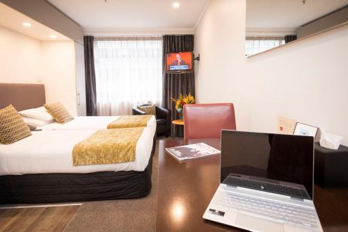 a hotel room with a bed and a desk with a laptop at Quest on Johnston Serviced Apartments in Wellington