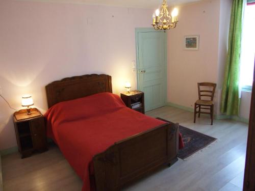 a bedroom with a red bed and two tables and a chair at Le Saule Argenté in La Villeneuve-au-Châtelot