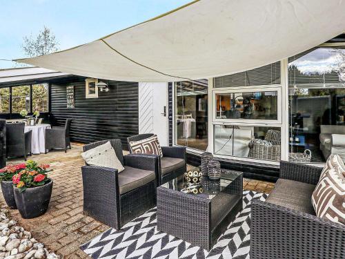 een patio met rieten meubels en een grote parasol bij 6 person holiday home in Hals in Hals