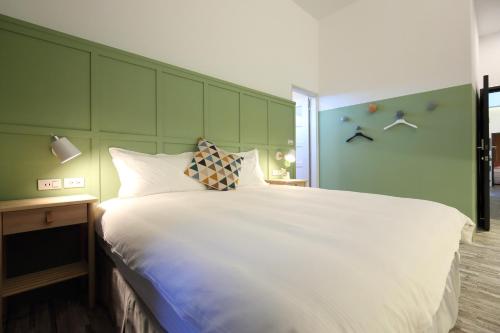 a bedroom with a large white bed with a green wall at Manting Homestay in Hualien City