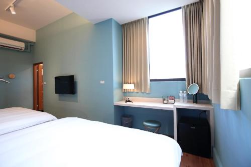 a bedroom with two beds and a desk and a window at Manting Homestay in Hualien City