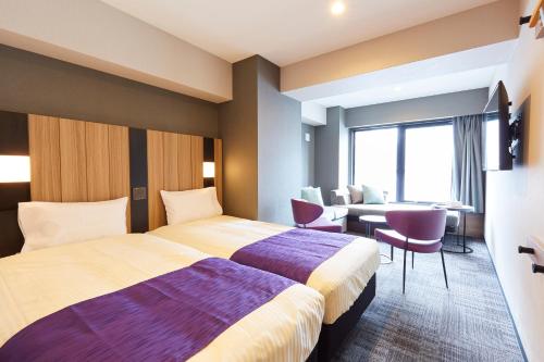 a hotel room with a bed and a table and chairs at hotel MONday Kyoto Karasuma Nijo in Kyoto