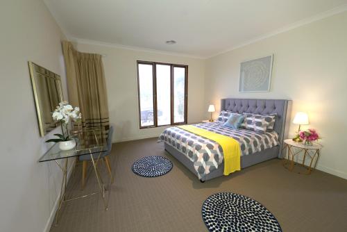 a bedroom with a bed and two tables with flowers at Stylish Luxe House For Big Group Near Shopping Center in Point Cook
