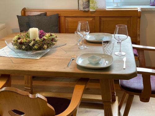 un tavolo in legno con due piatti e bicchieri da vino di Alpen Apartement a Hallstatt