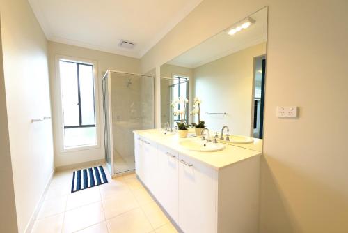 パッケナムにある6 Bedrooms Contemporary Big House at Pakenhemの洗面台2つとシャワー付きのバスルーム