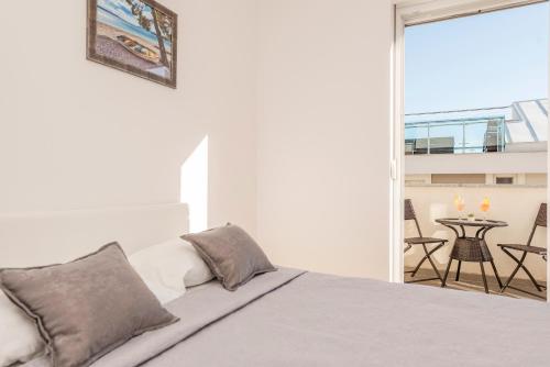 a bedroom with a bed and a balcony with a table at Enna house with private jacuzzi in Novalja