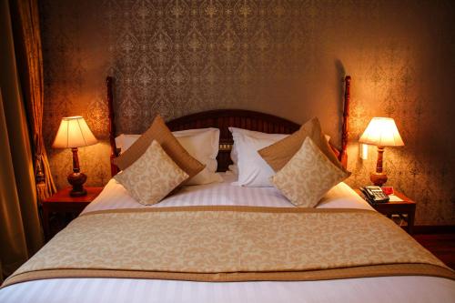 a bedroom with a bed with pillows and two lamps at LAOTEL VIENTIANE in Vientiane