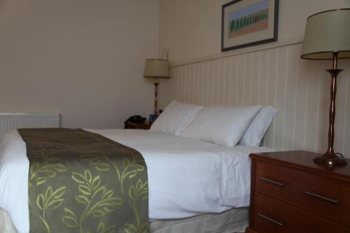 a hotel room with a bed and a dresser and lamp at Ivy House Country Hotel in Lowestoft