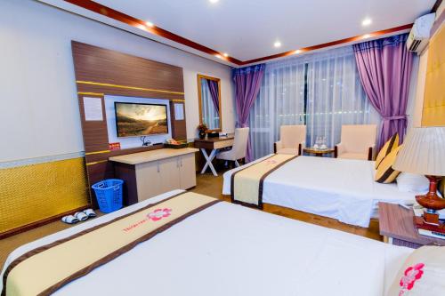 a hotel room with two beds and a desk at Hoa Dao Hotel in Hòa Bình