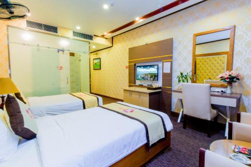 a hotel room with two beds and a desk at Hoa Dao Hotel in Hòa Bình