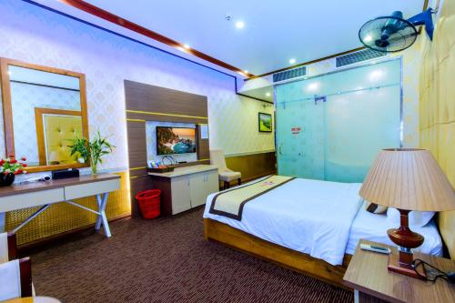 a bedroom with a bed and a desk and a mirror at Hoa Dao Hotel in Hòa Bình