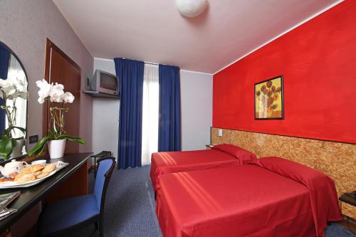 a hotel room with a red bed and a table at Hotel Residence Ducale in Porto Mantovano